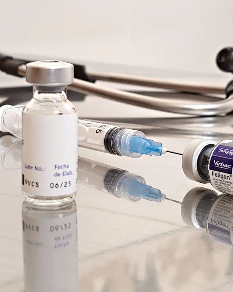Frascos de medicamento injetável, seringa e estetoscópio sobre a mesa