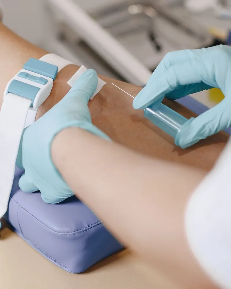 Coleta de sangue no braço, com garrote e luvas