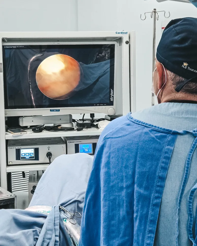 Monitor da cirurgia endoscópica com a imagem da câmera, e o Dr. Jorge Barros de costas