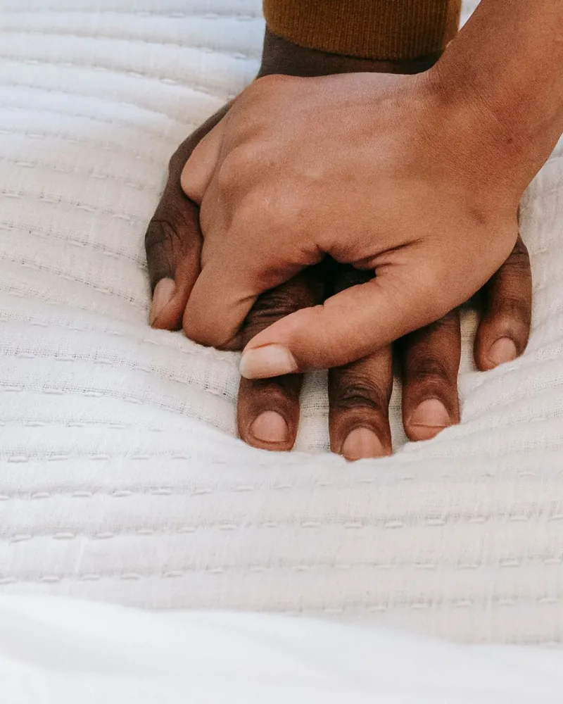 Casal sentado na cama, de mãos dadas